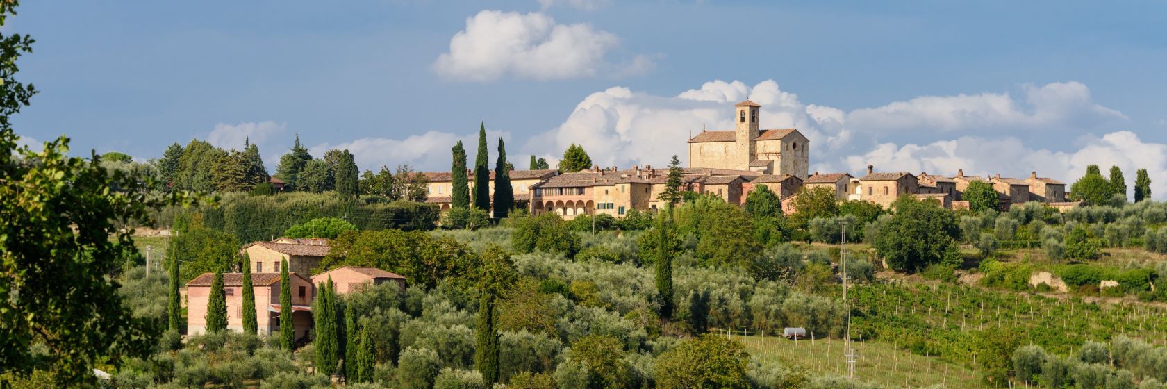 Klostret Certosa di Pontignano med odlingar och uppstickande cypresser i frgrunden.